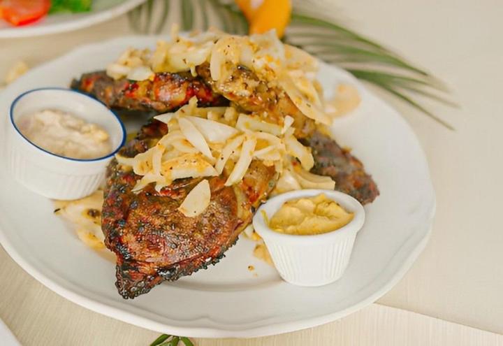 Agneau mariné et grillé fini au four avec oignons sautés servi avec votre choix d'accompagnement.